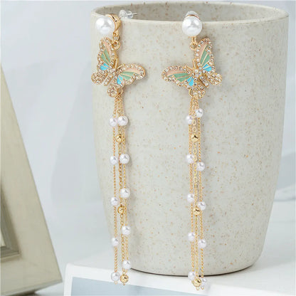 Tassel butterfly earrings with pearls displayed on beige pot