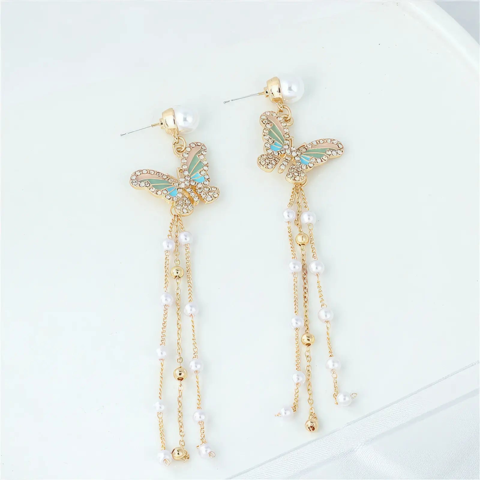 Tassel butterfly earrings with pearls displayed on white plate