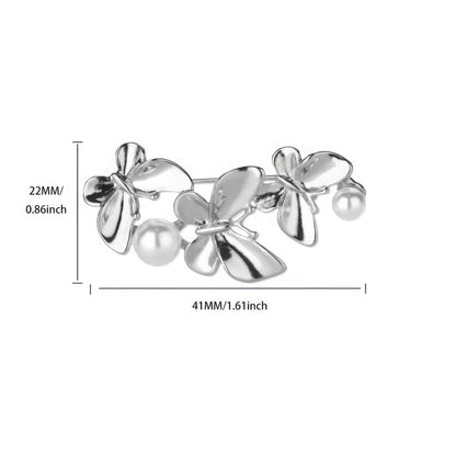 Gold and silver three - butterfly brooches with pearls, displayed on white curved surface, showcasing variety