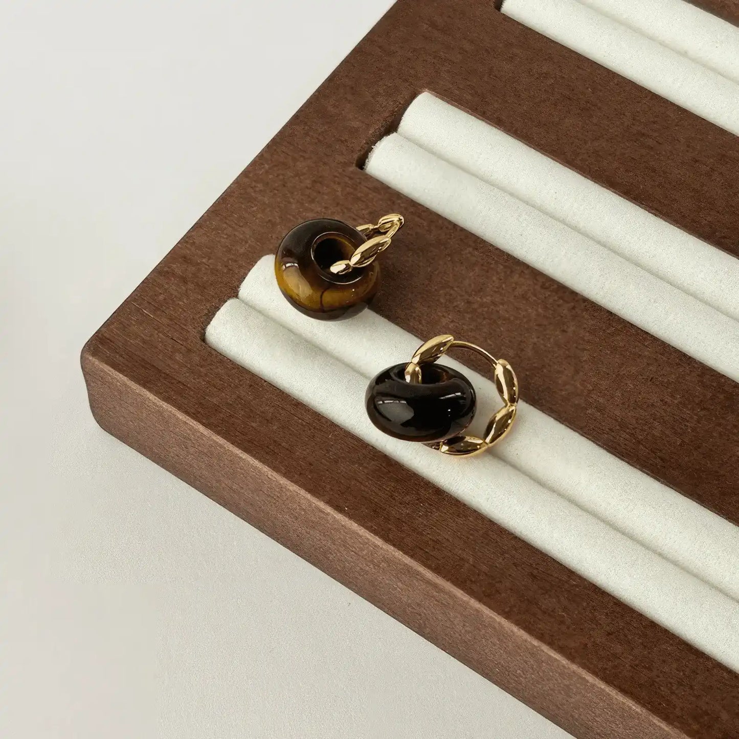 Tiger eye stone hoop earrings, gold - tone, displayed on wood and white stand
