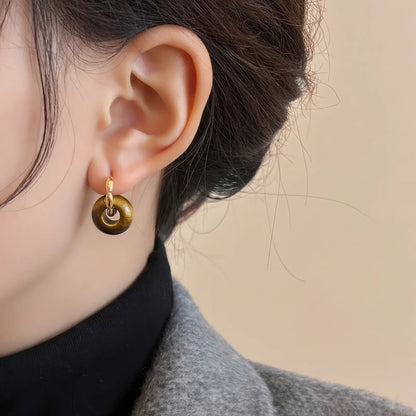 Tiger eye stone hoop earrings, gold - tone, worn on ear with gray coat