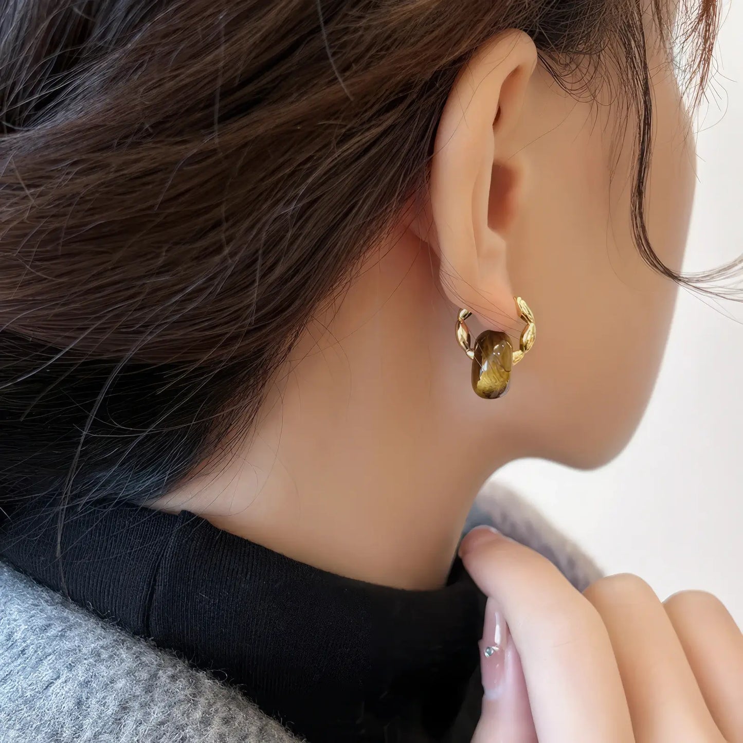 Tiger eye stone hoop earrings, gold - tone, worn on ear with hand near neck