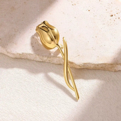 Gold tulip brooch placed on beige stone, side view, highlighting texture