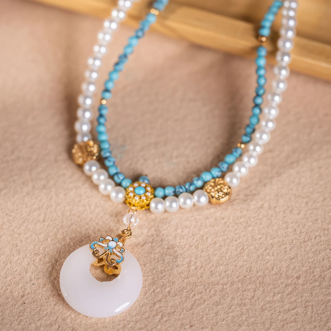 Turquoise peace buckle necklace with pearls, displayed on light surface