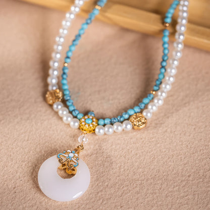 Turquoise peace buckle necklace with pearls, displayed on light surface