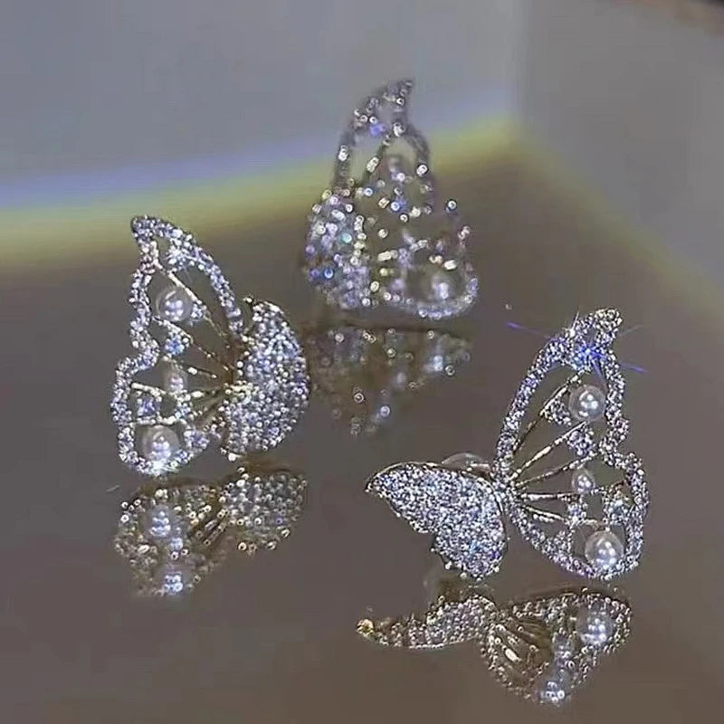 Silver two - way wear butterfly diamond earrings, isolated on reflective surface