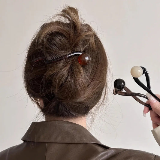 Vintage pearl twist clip worn in an updo hairstyle, brown clothing background