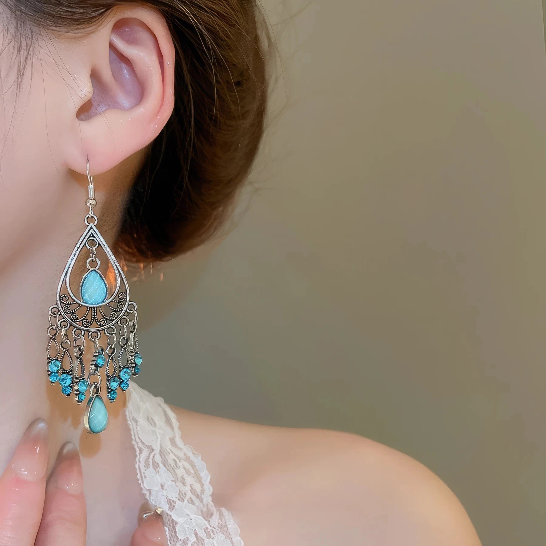 Water drop tassel earrings, blue stones with silver - tone filigree, worn on ear with lace top (side view)