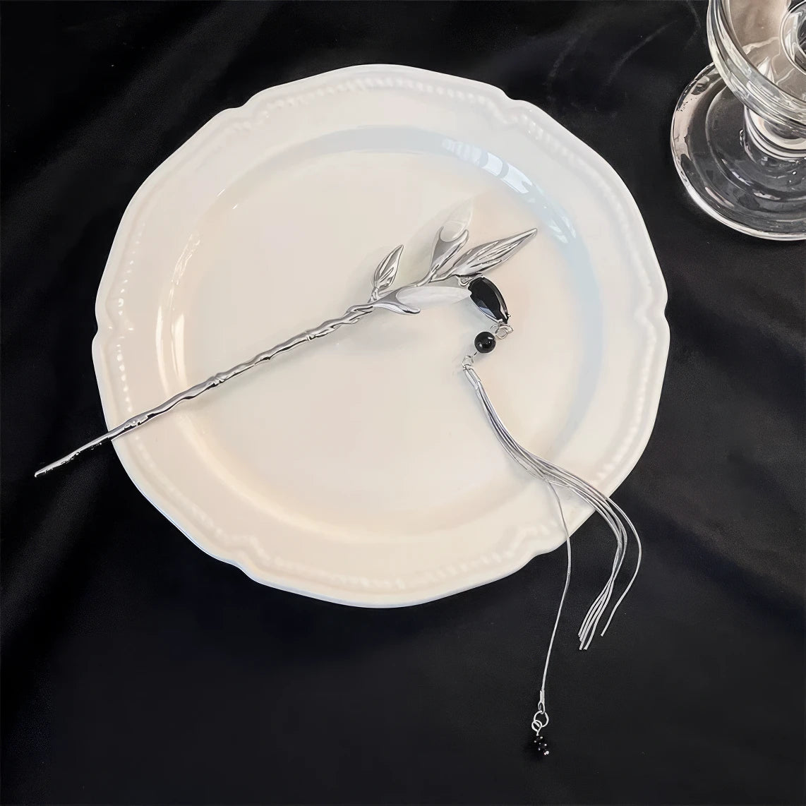 Silver white jade bamboo tassel hairpin displayed on a white plate, dark background