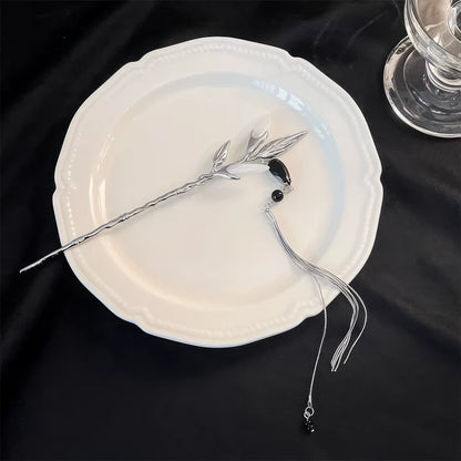 Silver white jade bamboo tassel hairpin displayed on a white plate, dark background