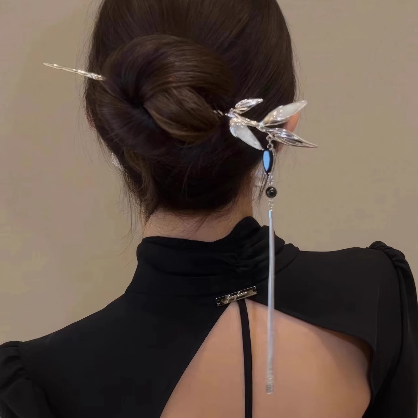 Silver white jade bamboo tassel hairpin worn in an updo hairstyle, black clothing background