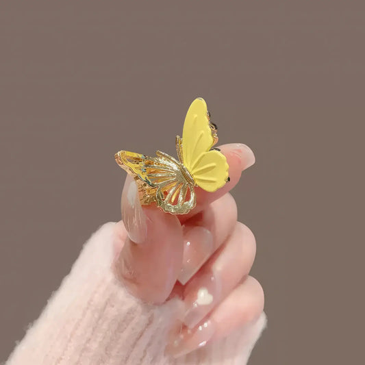 Yellow butterfly mini claw clip, close - up held by hand