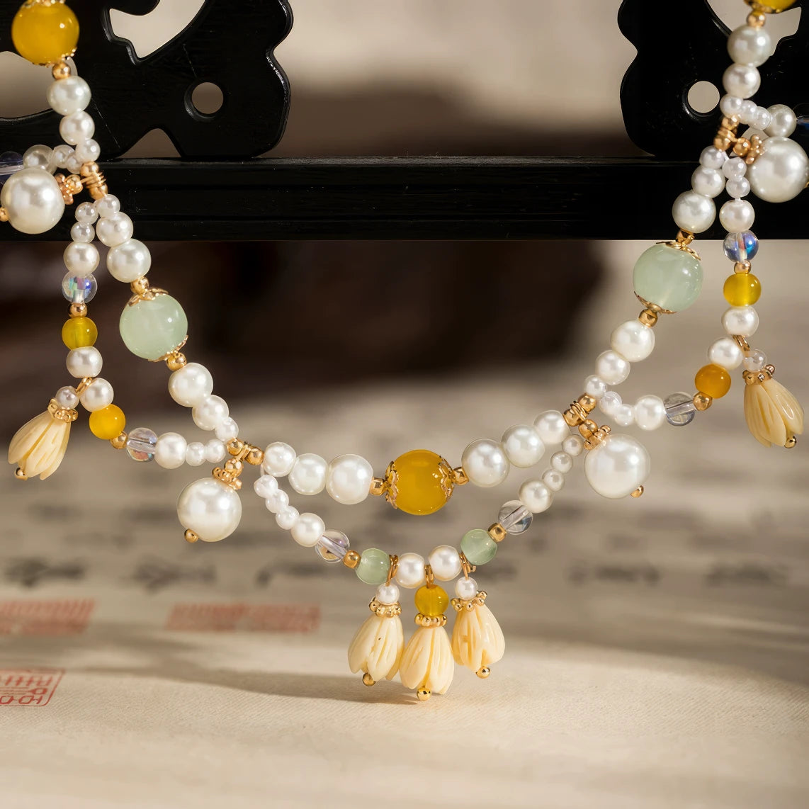 Yellow lily - of - valley necklace with pearls and beads, displayed on calligraphy paper, close - up view