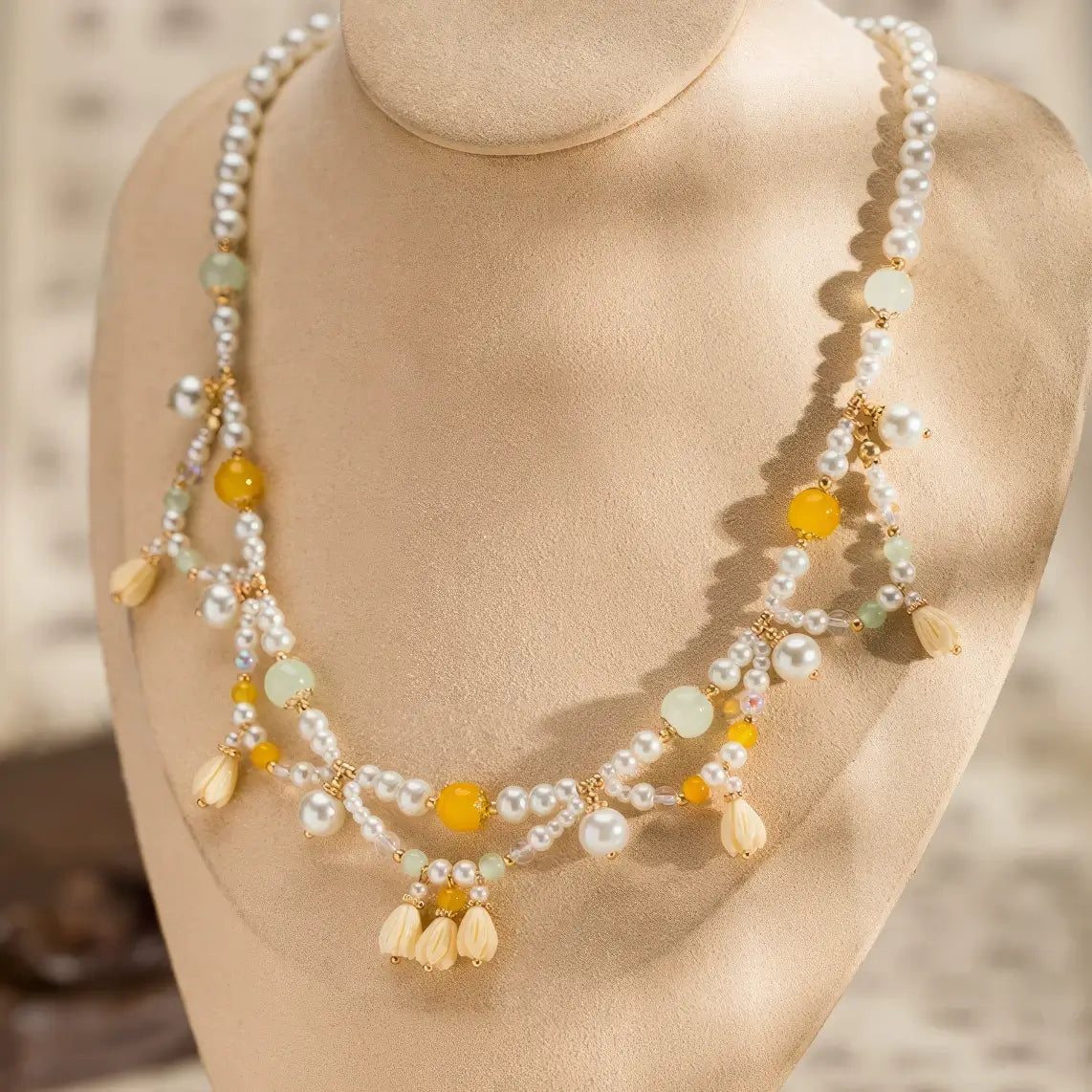 Yellow lily - of - valley necklace with pearls and beads, displayed on mannequin, light background