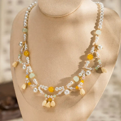 Yellow lily - of - valley necklace with pearls and beads, displayed on mannequin, light background