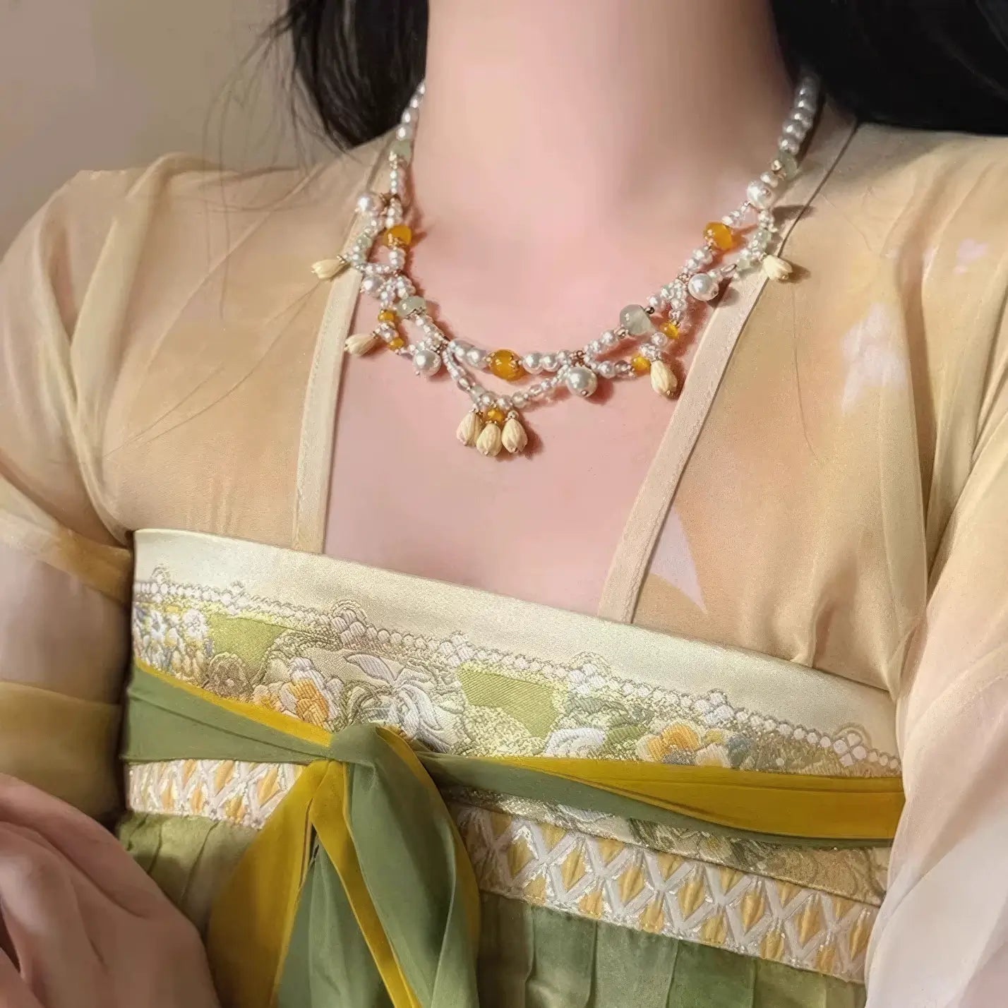 Woman wearing yellow lily - of - valley necklace with pearls and beads, traditional clothing background